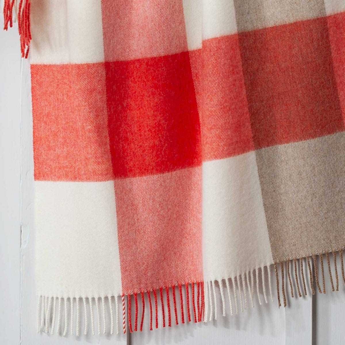 A close-up detailing the block check colours of cream, red and beige. Made in Britain. 100% Merino Wool.