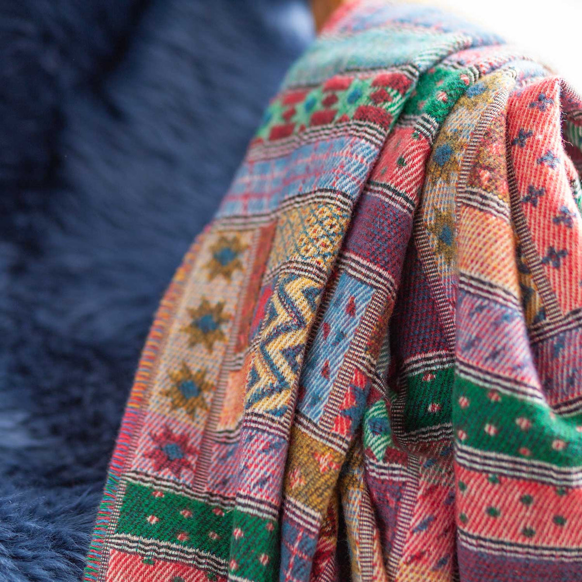 Close-up of the Hebrides Merino Throw in Jura, woven in a multicoloured pattern of red, pink, green and blue