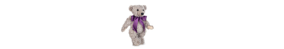Chester teddy bear in his purple bow, stands at 12 inches tall. Fully jointed; soft grey mohair, with light stone felt paws.
