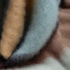 A close-up highlighting the cool coastal tones of pale green, blue, yellow and brown. Bringing a subtle hint of the beach to this beautifully woven blanket. Made in Spain.