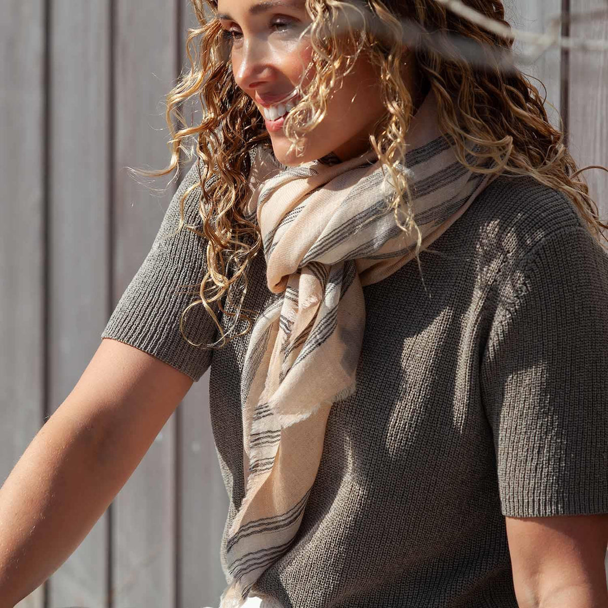 A model showing just one of many ways to wear this luxurious, soft and light cashmere square scarf. Available in Light Blue, Silver, Sage, Navy, Coral Red and Sahara.