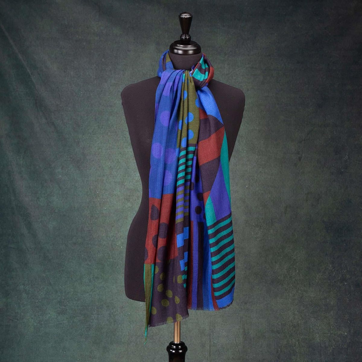 Showcasing the amazing drape of the soft merino and silk shawl. Rich dark blues, olive green, mint green and chocolate brown, with a geometric pattern. Made in India. 90 x 190 CMS.