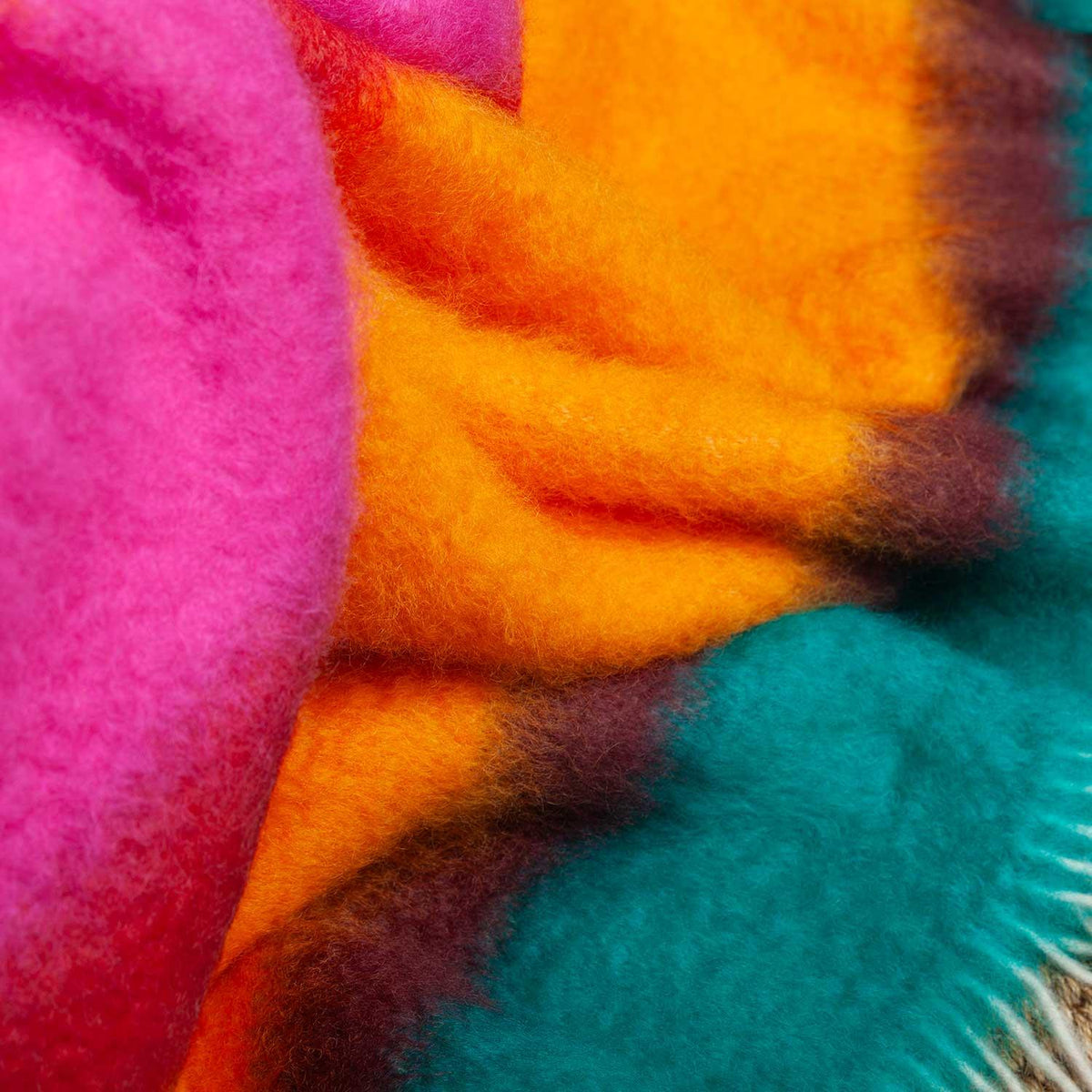 A close-up of the Festival Mohair Blanket Caribbean,  a rainbow of bold stripes of colour and character, finished with a cream tasselled fringe.  50% Mohair, 48% Wool, 2% Polyamide.
