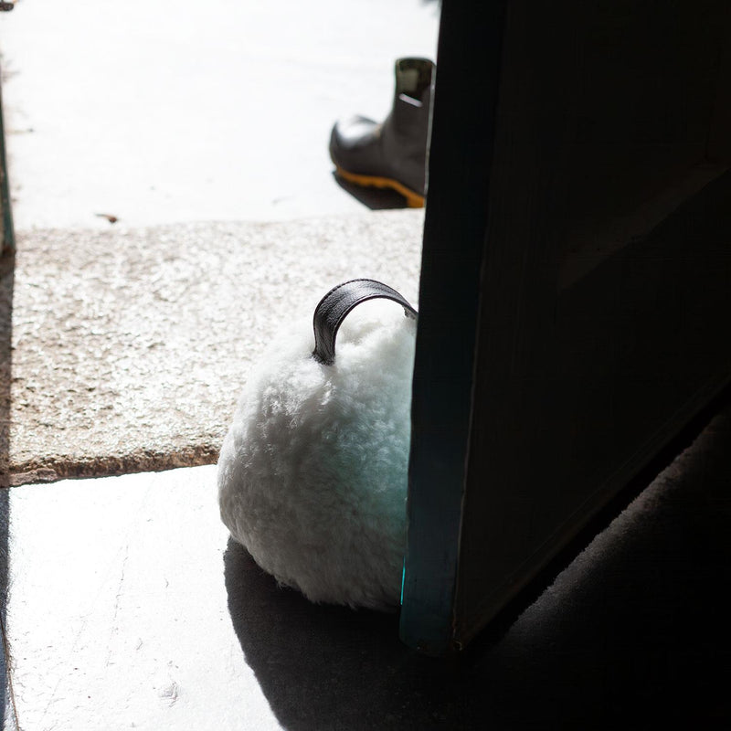 Sheepskin Doorstop in white curly sheepskin with dark brown leather carry handle